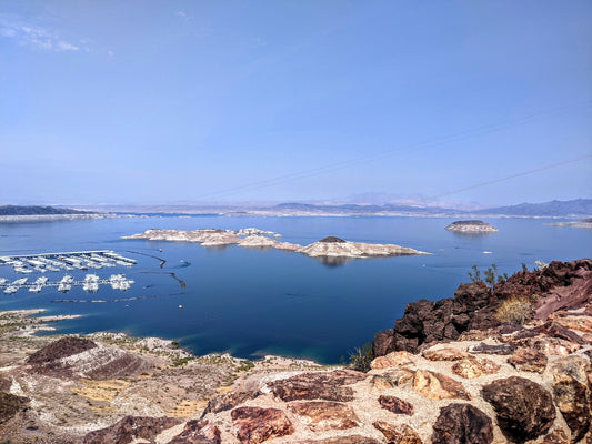 body of water near brown rocky mountain under blue sky during daytime